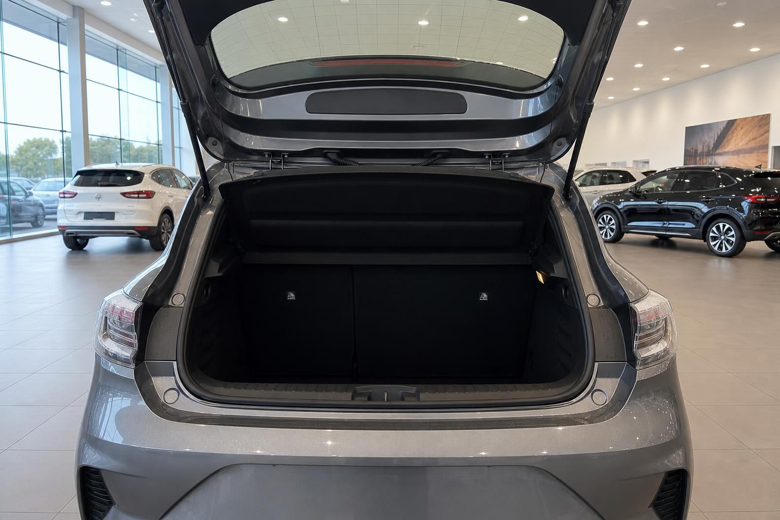 Kofferraum eines grauen Fahrzeugs mit geöffneter Heckklappe im Autohaus-Showroom