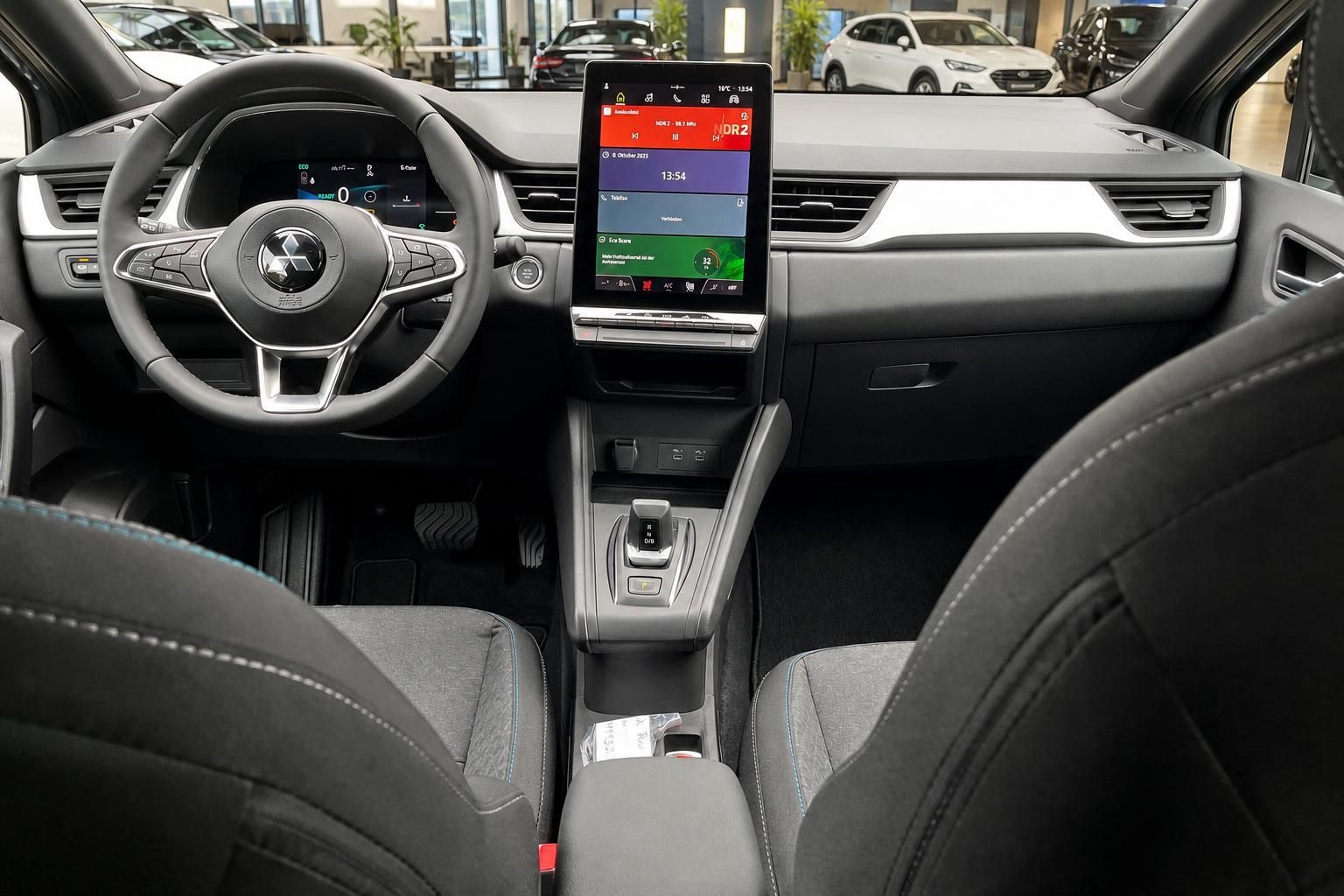 Cockpit-Ansicht mit Lenkrad, Touchscreen und Vordersitzen im Fahrzeug