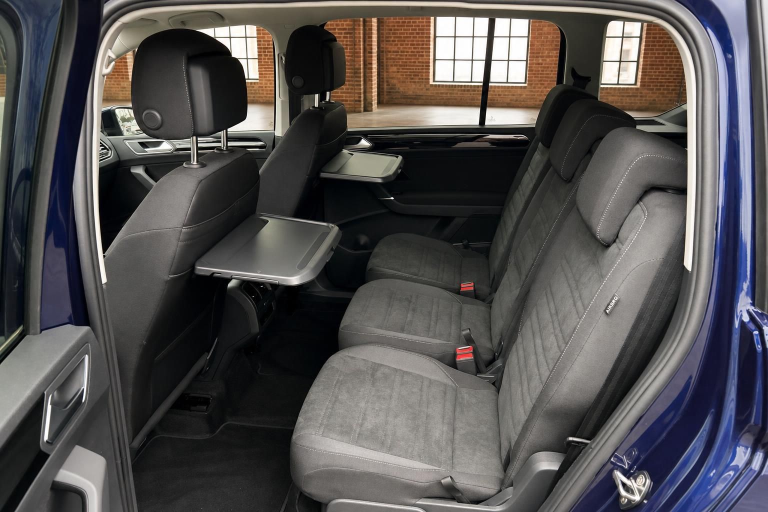 VW Fondsitze mit Klapptischen und Kopfstuetzen im blauen Van Innenraum