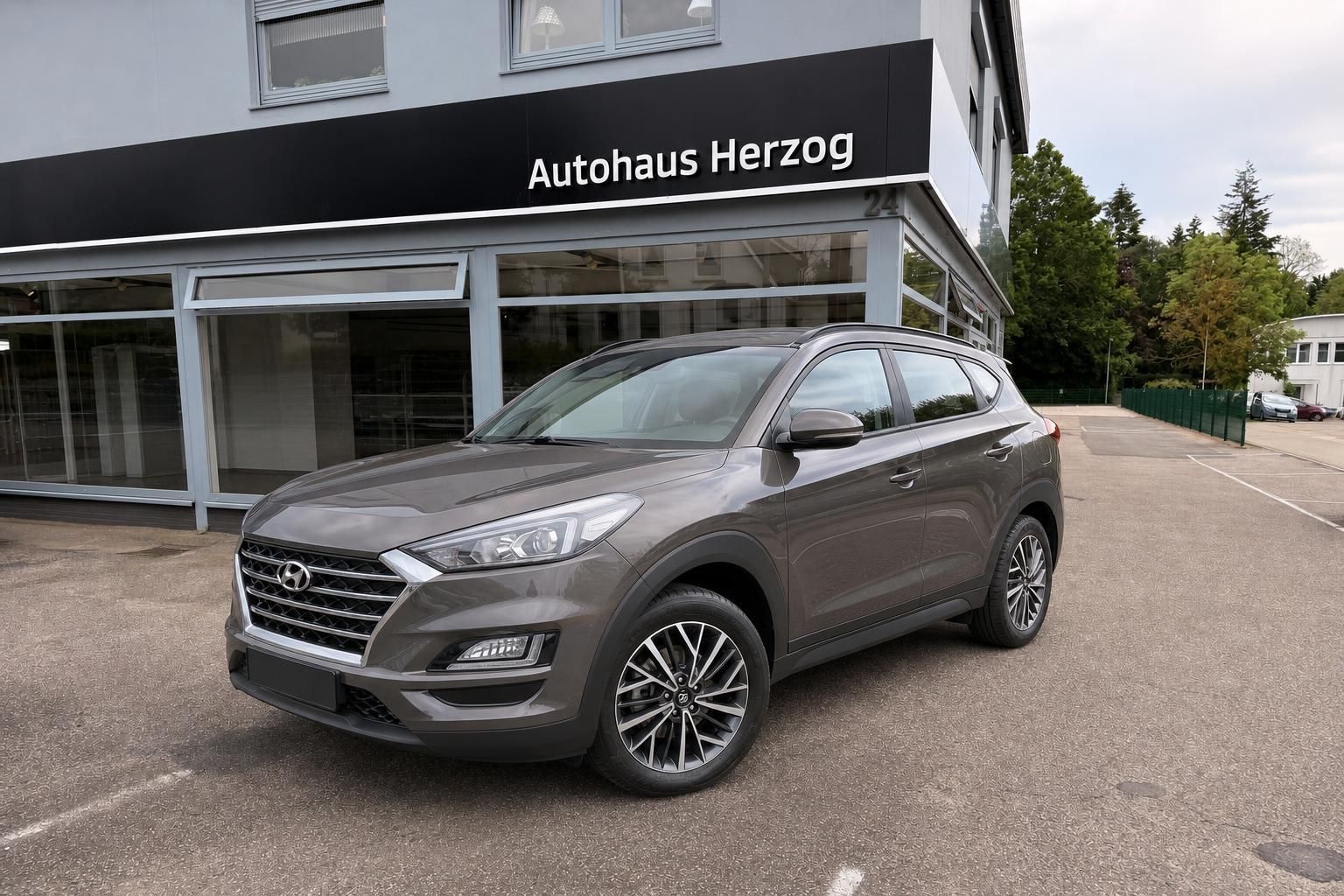 Hyundai Tucson SUV in Braun, Frontansicht vor Autohaus Herzog