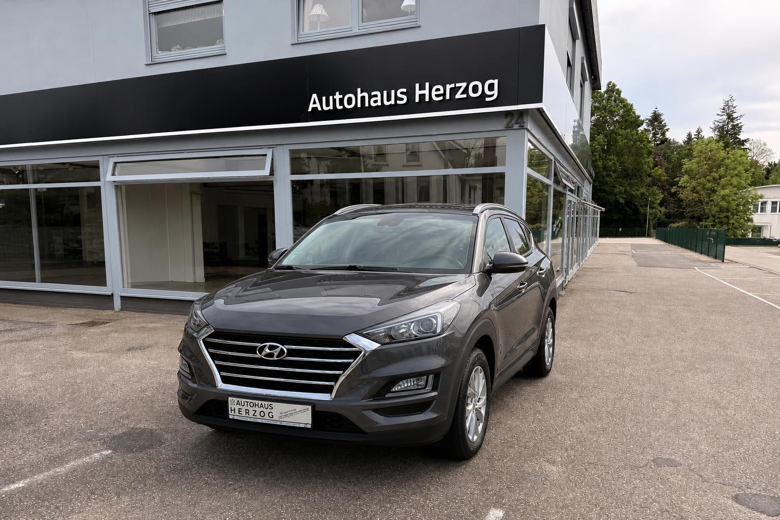 Hyundai Tucson grau Front schraeg vor Autohaus Herzog