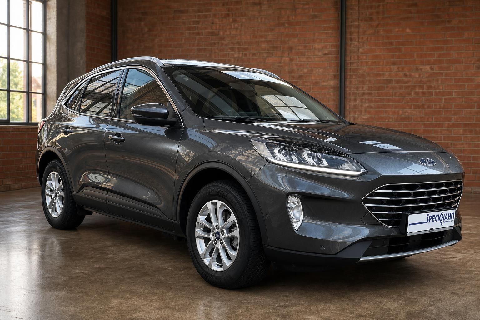 Ford Kuga grau Frontansicht SUV vor Backsteinwand im Showroom