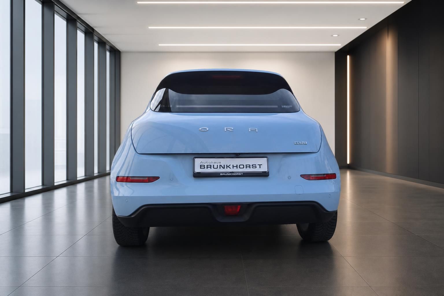 Hellblauer Elektro-Kleinwagen von hinten im Autohaus - Heckansicht mit schwarzem Panoramadach