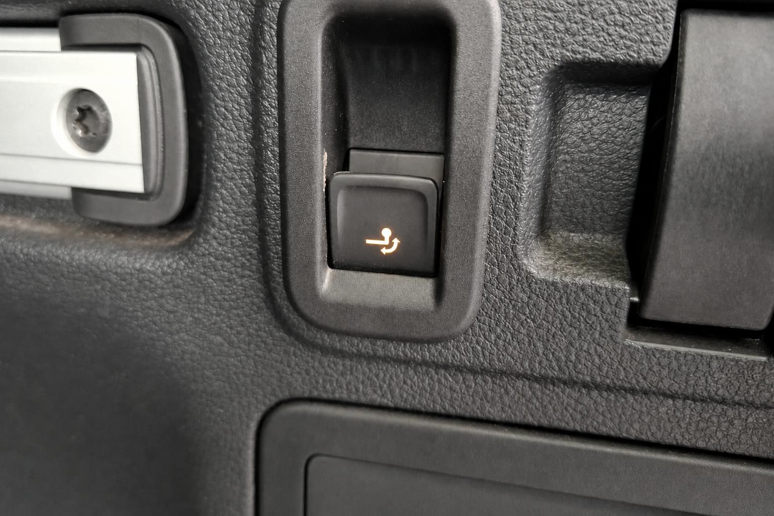Beleuchteter Schalter im Fahrzeug-Innenraum mit orange leuchtendem Symbol