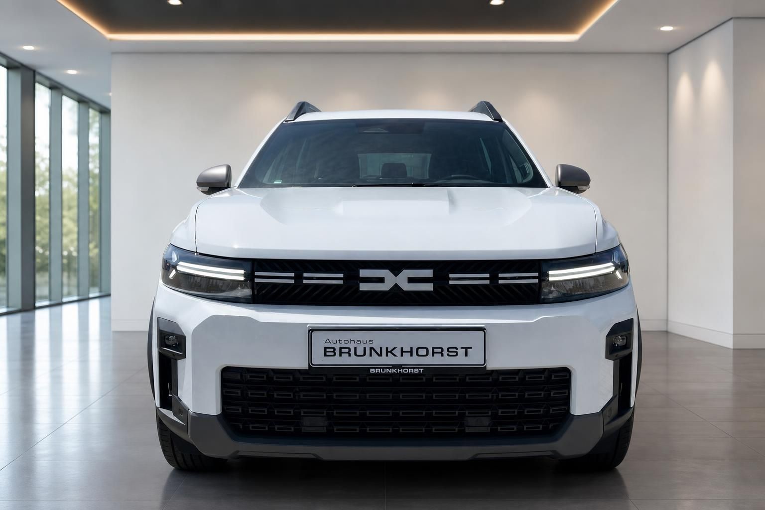 Dacia Bigster weiß, Frontansicht mit LED-Scheinwerfern im Showroom