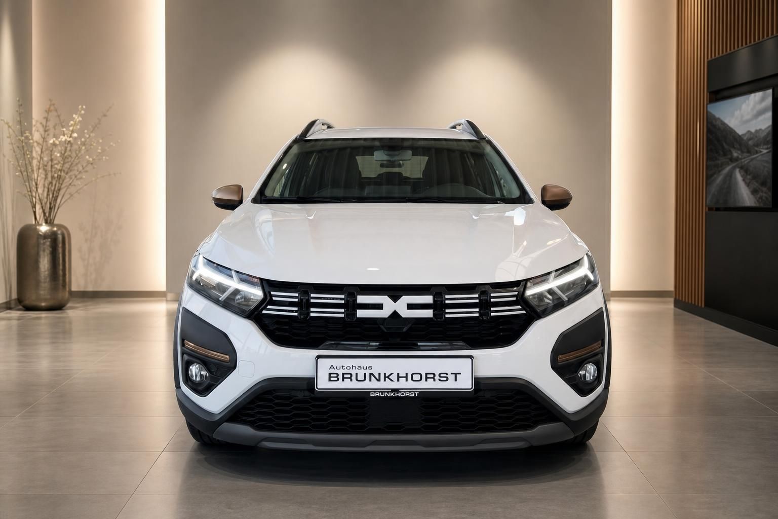 Weißer Dacia SUV Frontansicht mit schwarzem Kühlergrill und LED-Scheinwerfern im Showroom