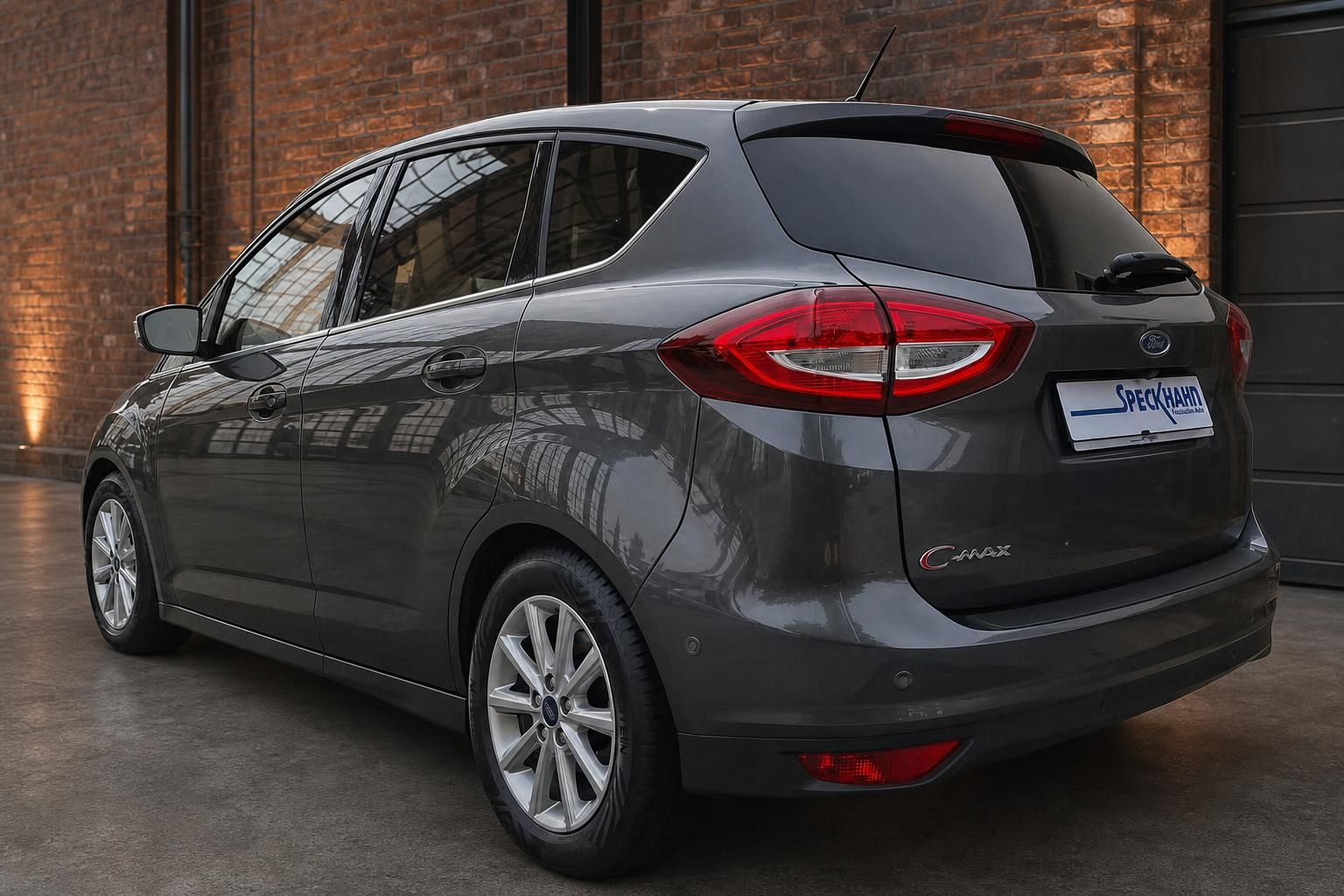 Ford C-MAX in Anthrazit, Heckansicht seitlich vor Backsteinwand