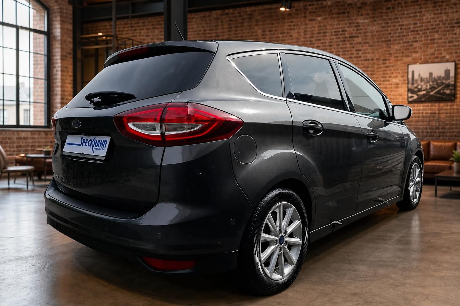 Ford C-MAX in Dunkelgrau, Heckansicht schraeg im Showroom