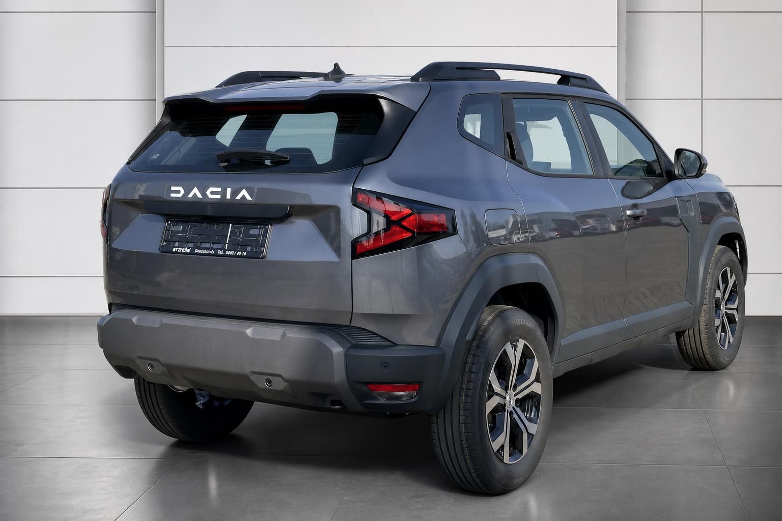 Dacia Duster grau Heckansicht links im Autohaus mit Anhängerkupplung und Alufelgen