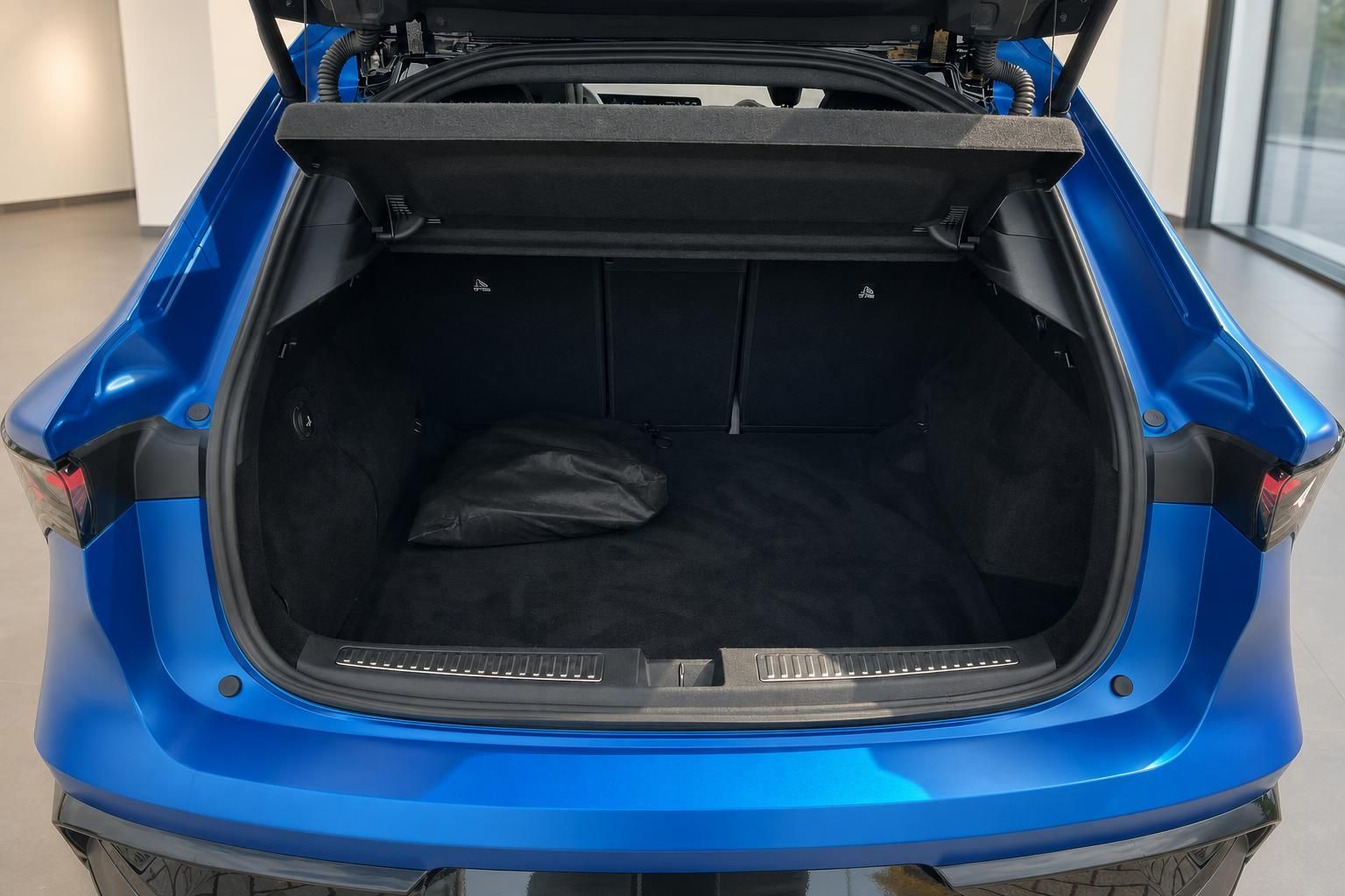 Kofferraum eines blauen Fahrzeugs mit geöffneter Heckklappe und schwarzer Innenausstattung