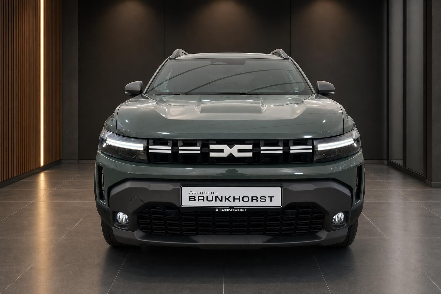 Dacia SUV grün metallic Frontansicht im Autohaus Showroom mit LED-Scheinwerfern und Kühlergrill