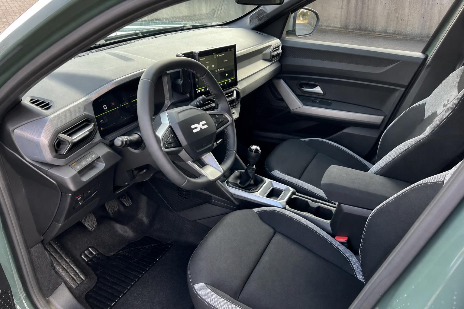 Dacia Fahrzeug Innenraum mit Lenkrad, Armaturenbrett und digitalen Displays in grau-schwarzer Ausstattung