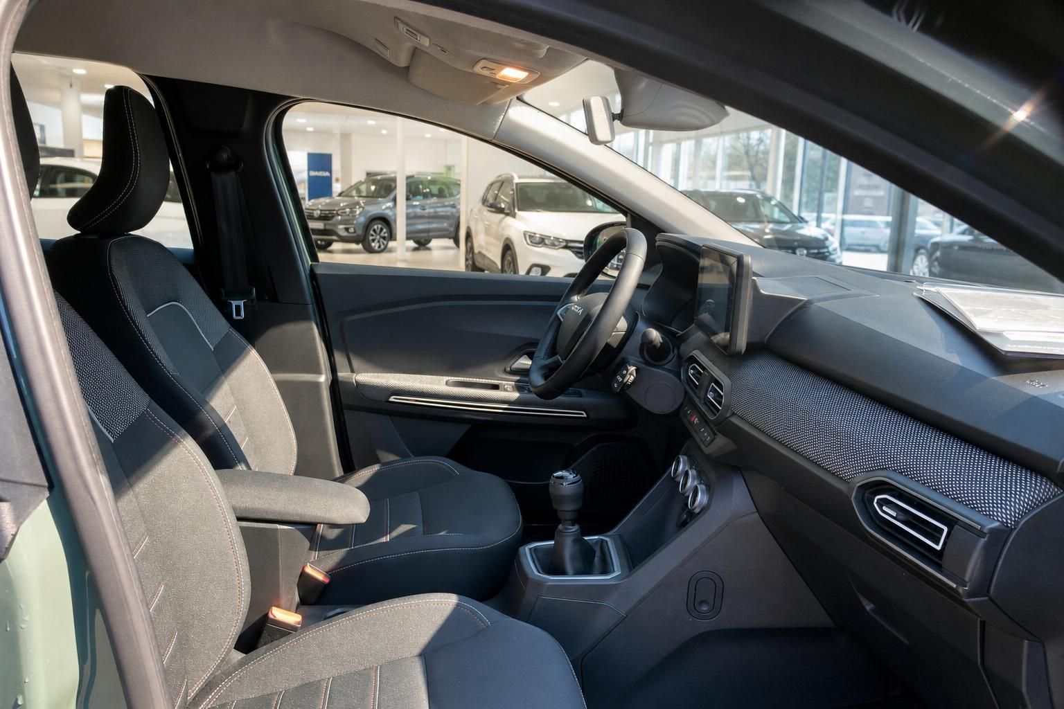 Dacia Innenraum mit Fahrer- und Beifahrersitz, Mittelkonsole mit Schaltgetriebe und Armaturenbrett