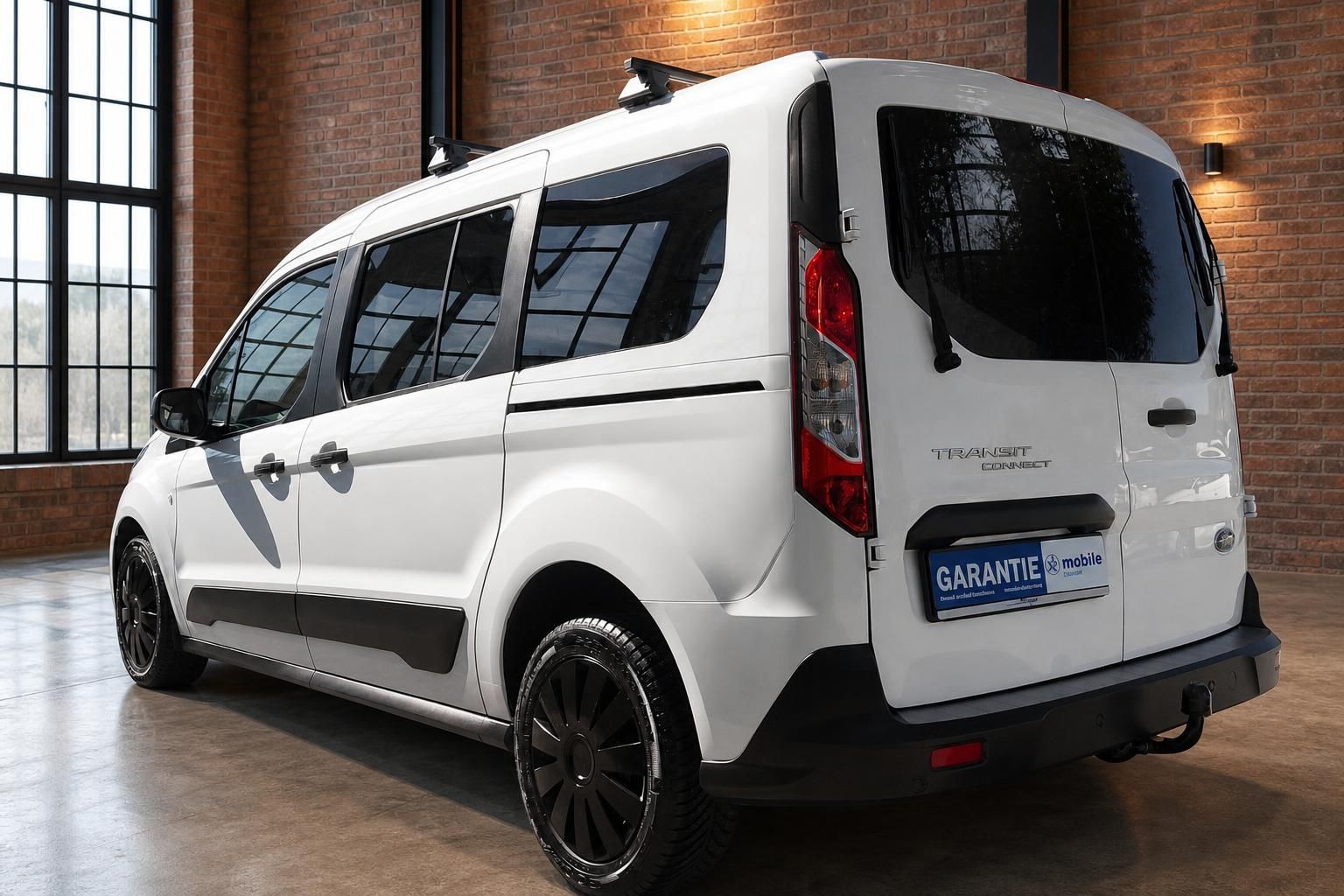 Ford Transit Connect weiss Heckansicht schraeg links mit schwarzen Felgen im Showroom