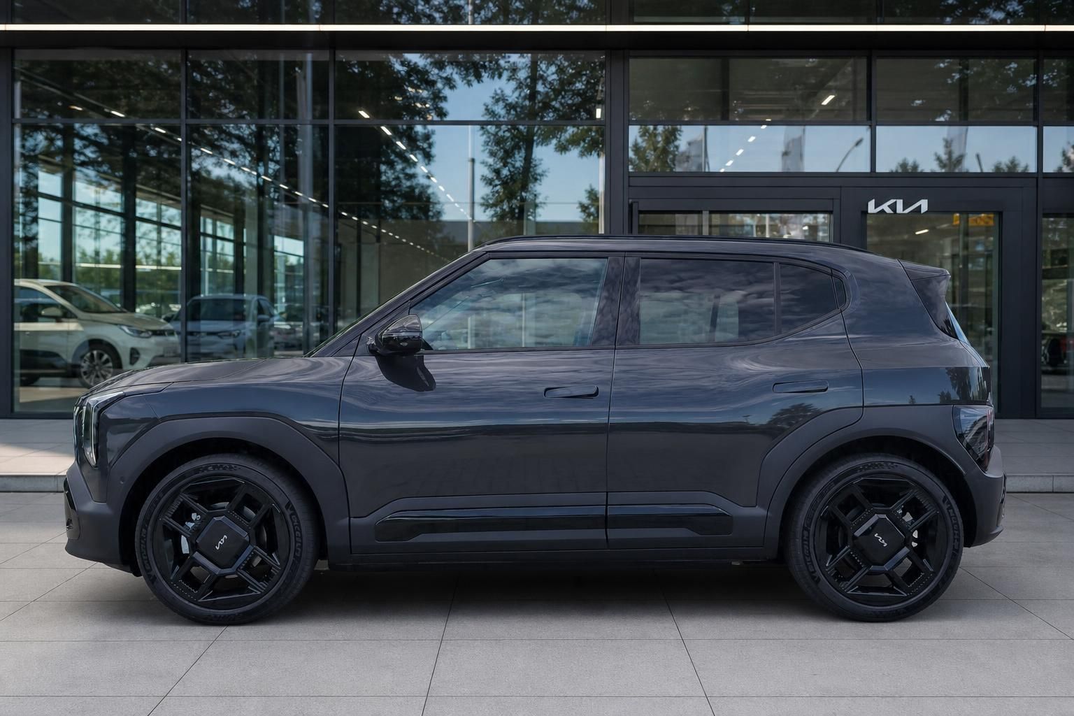 Kia EV9 in Dunkelgrau, Seitenansicht vor Autohaus Fassade