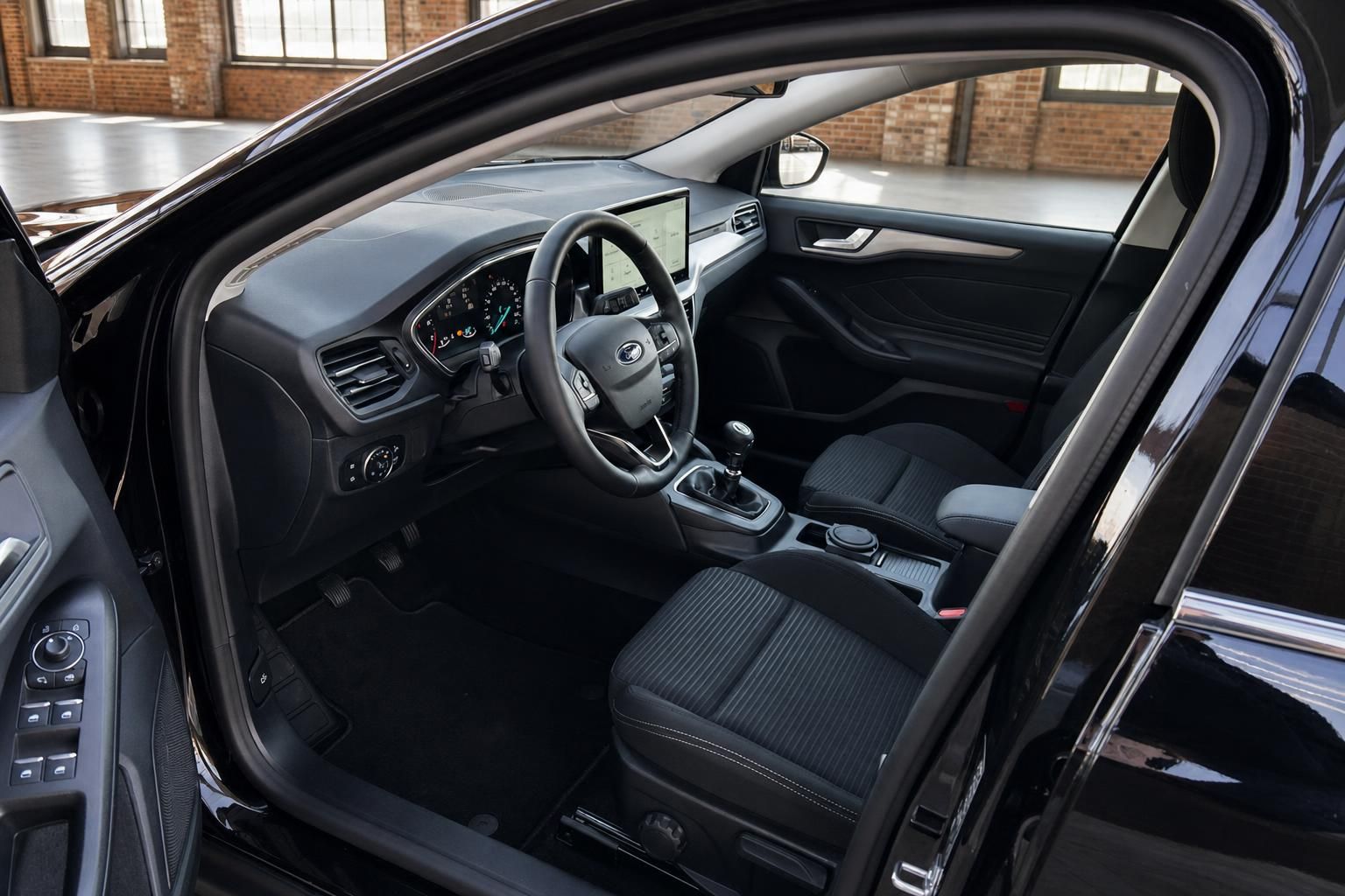 Ford Focus Innenraum – Cockpit mit Lenkrad, Touchscreen, Schalthebel und schwarzen Stoffsitzen