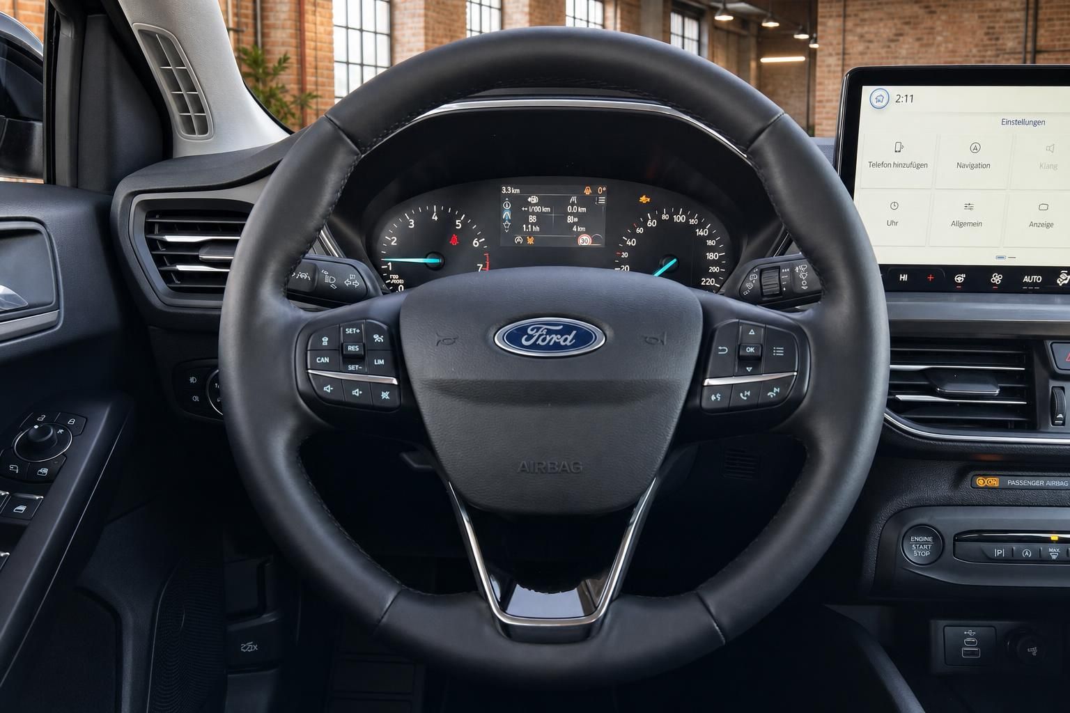Ford Focus Lenkrad mit Multifunktionstasten, Tachometer und Infotainment-Display im Hintergrund