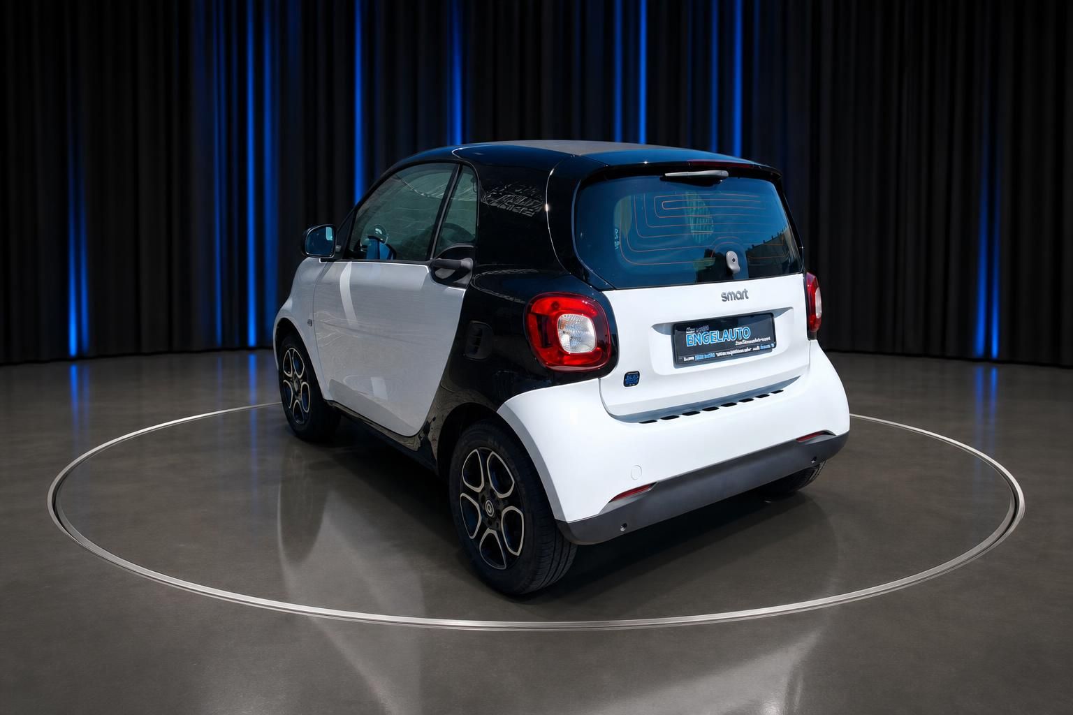 Smart Fortwo Heckansicht weiss-schwarz vor dunklem Vorhang
