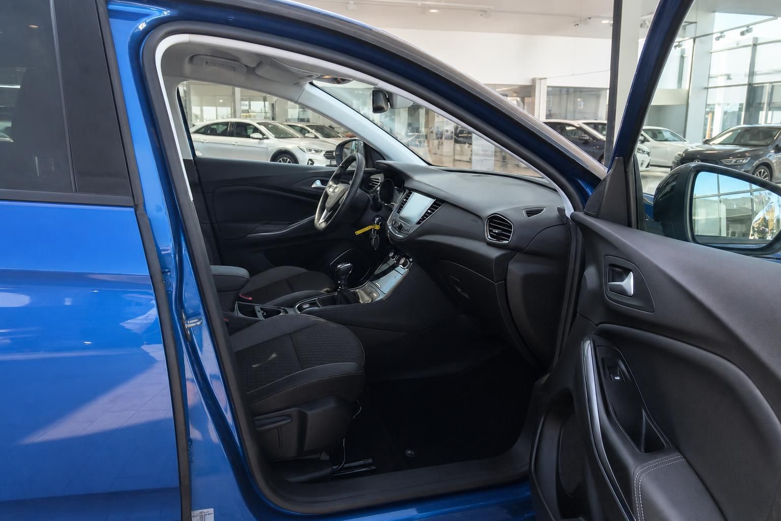 Fahrzeug Innenraum mit schwarzen Sitzen und offener Fahrertür in blauem Auto im Autohaus
