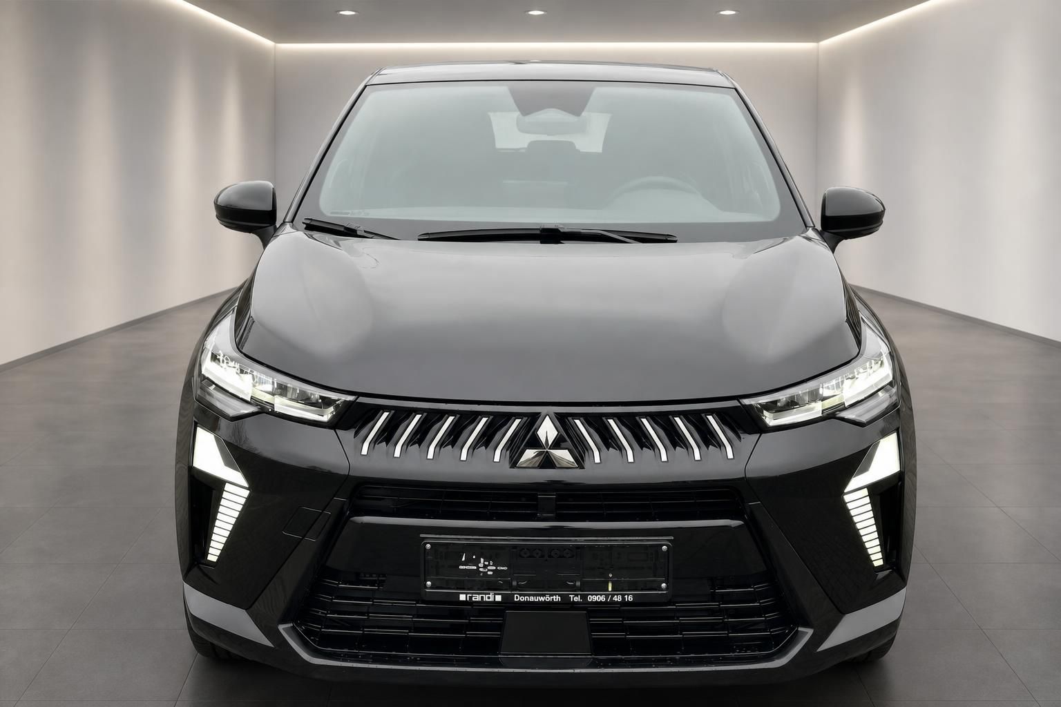 Mitsubishi SUV schwarz Frontansicht im Showroom – markantes Kühlergrill-Design mit Dreizack-Logo