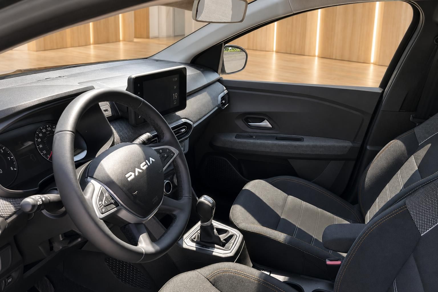 Dacia Innenraum Fahrerseite mit Lenkrad, Schaltgetriebe, Vordersitzen und Touchscreen-Display