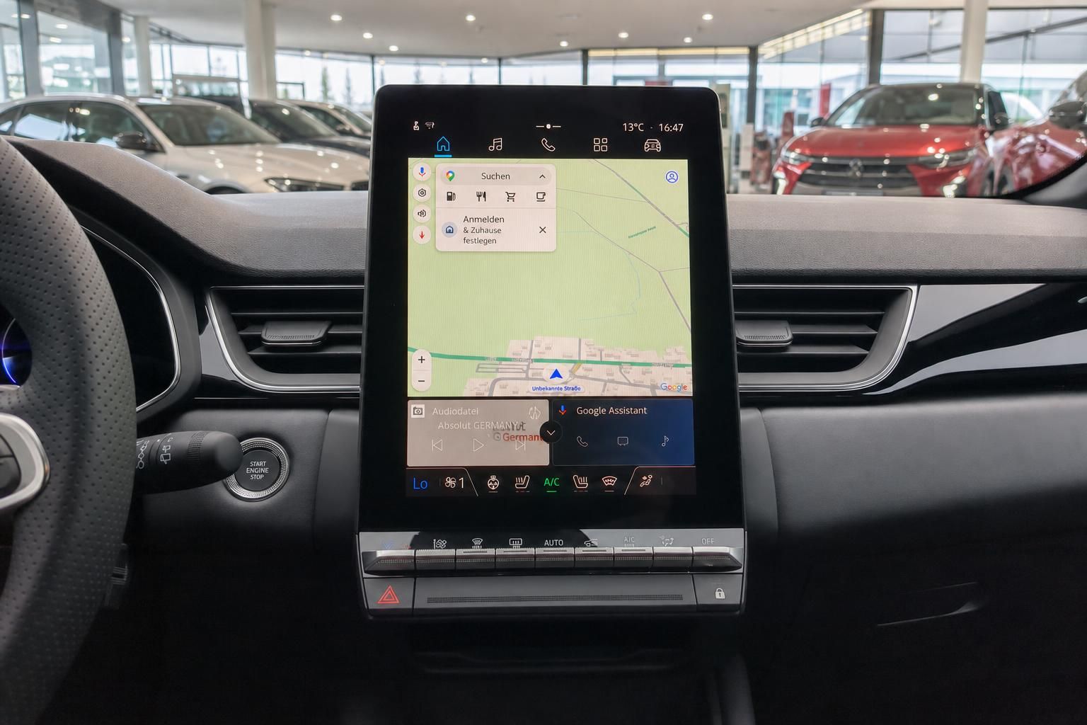 Modernes Navigationssystem mit Touchscreen im Fahrzeug-Cockpit mit Autohaus im Hintergrund