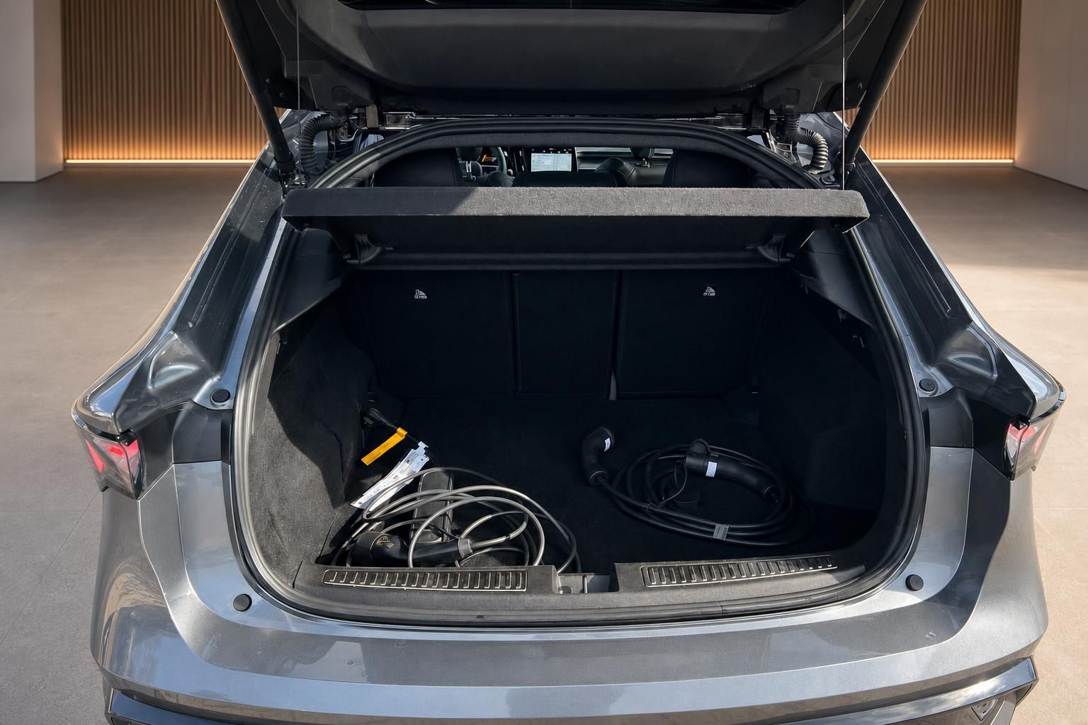Geöffneter Kofferraum eines grauen Fahrzeugs mit Ladekabel für Elektroauto im Showroom
