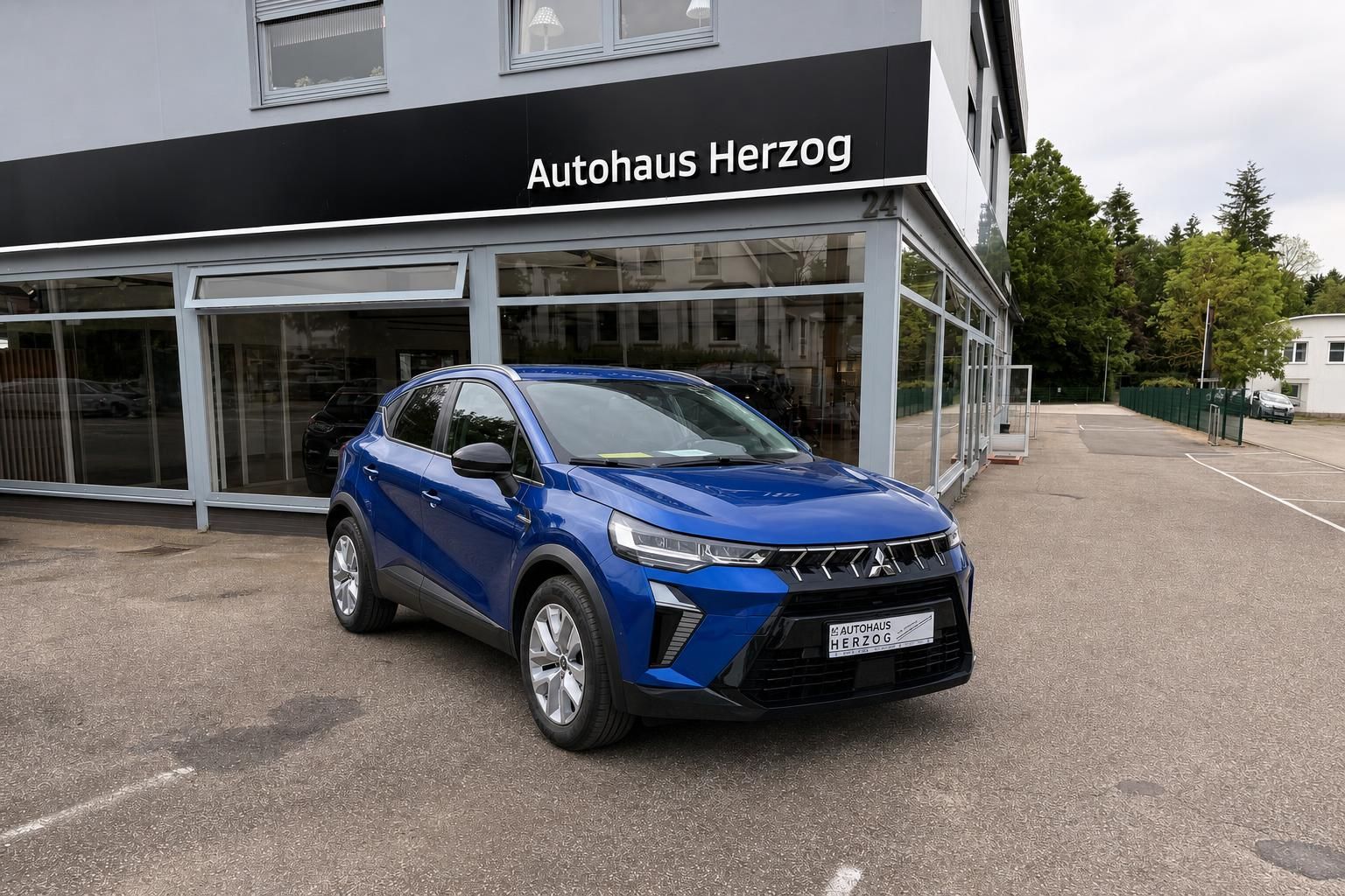 Blauer Mitsubishi SUV Frontansicht vor Autohaus Herzog Gebäude