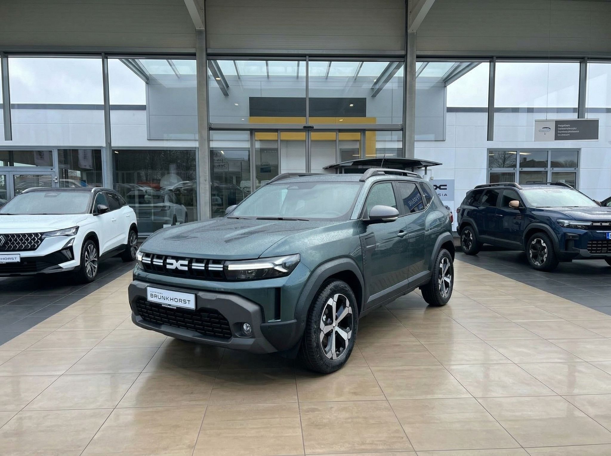 Dacia Duster SUV in grüner Metallic-Lackierung im Autohaus Showroom mit Dachträger