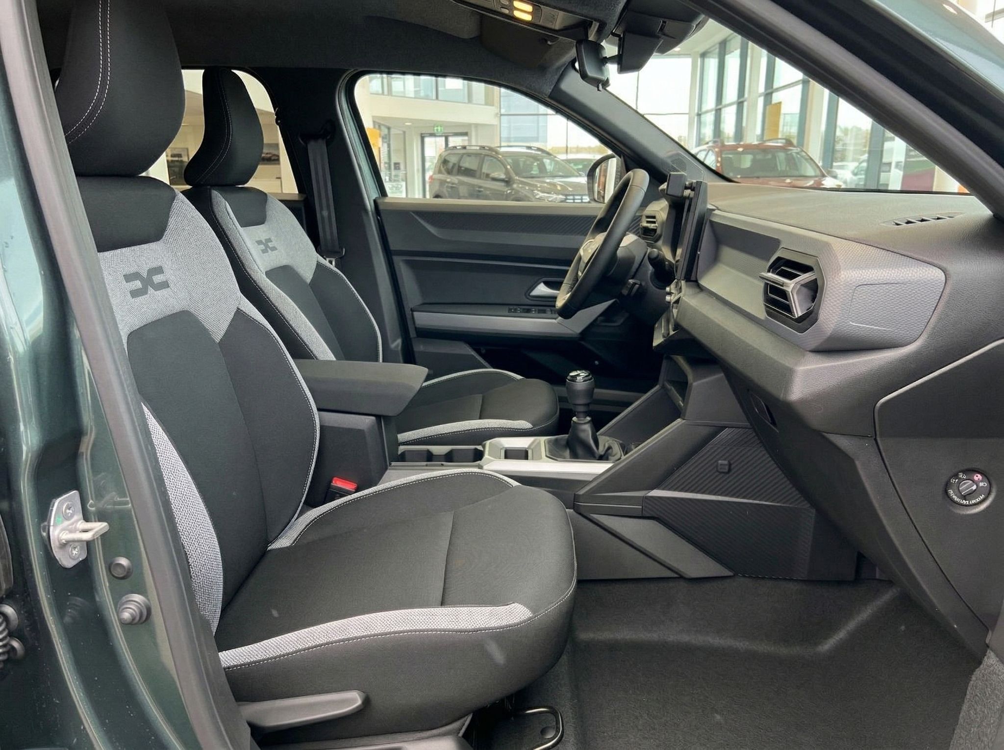 Fahrzeuginnenraum mit Fahrer- und Beifahrersitzen in grau-weißer Ausstattung