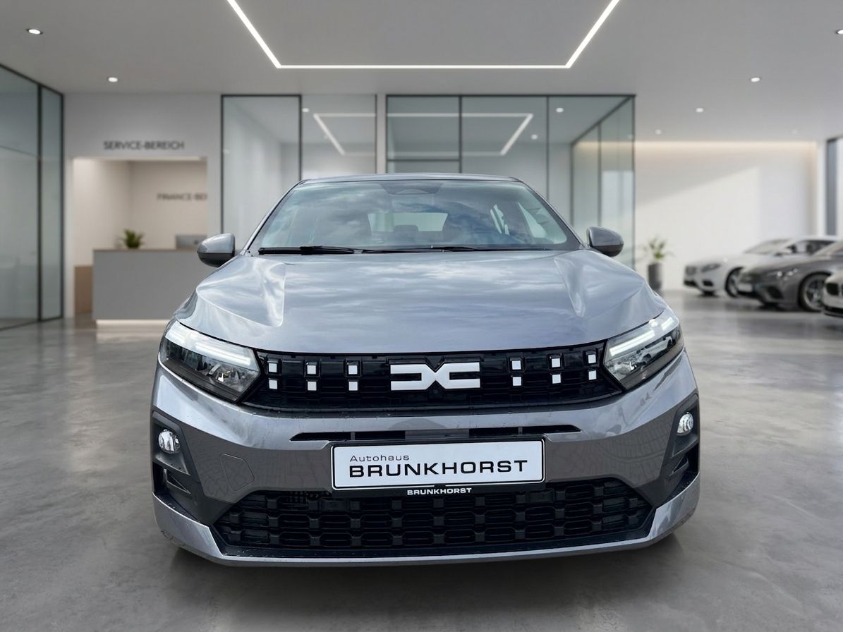 Dacia Fahrzeug grau - Frontansicht mit DC Logo im modernen Autohaus