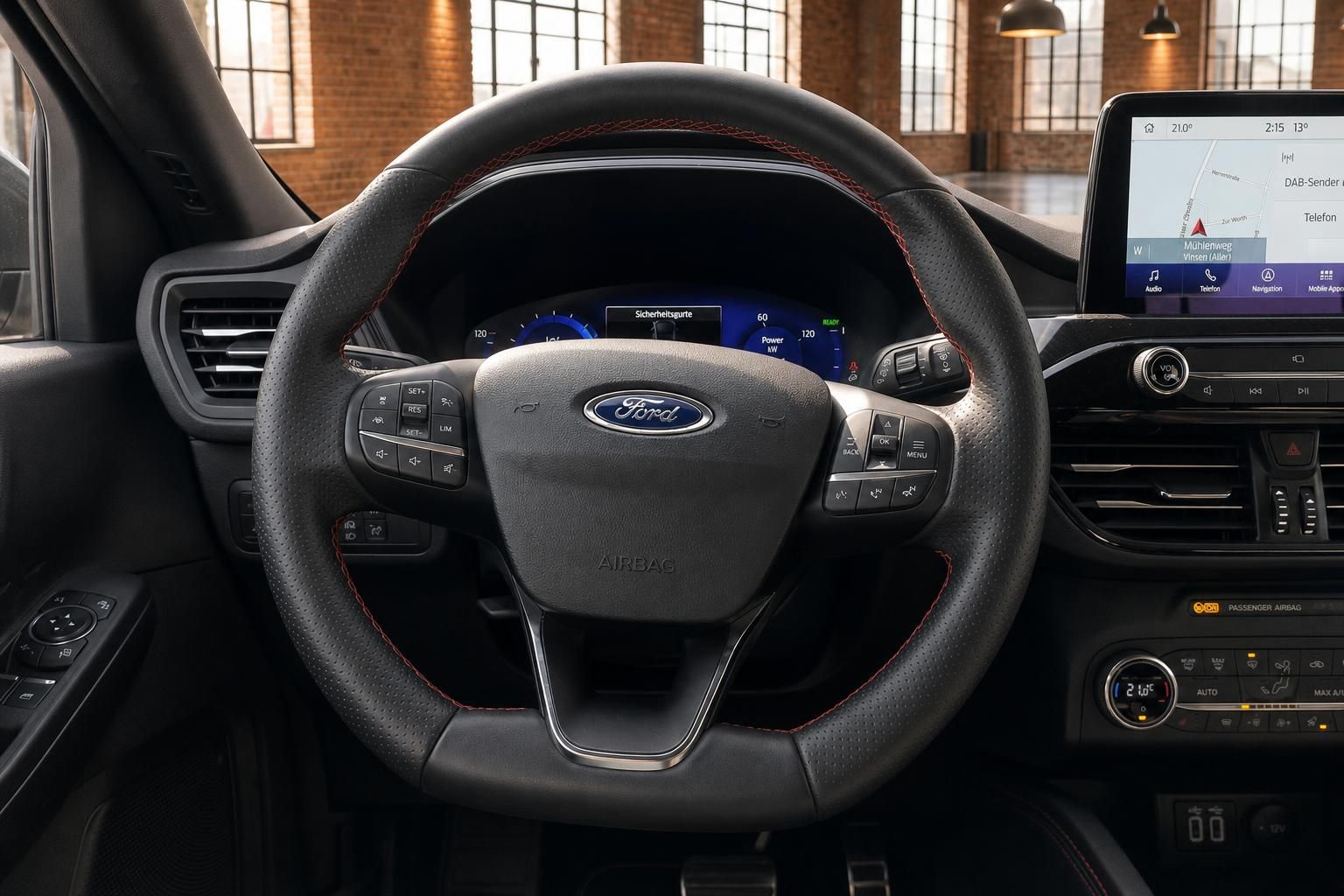 Ford Kuga Lenkrad Nahaufnahme mit Ford Logo, roten Ziernähten, Multifunktionstasten und Tacho