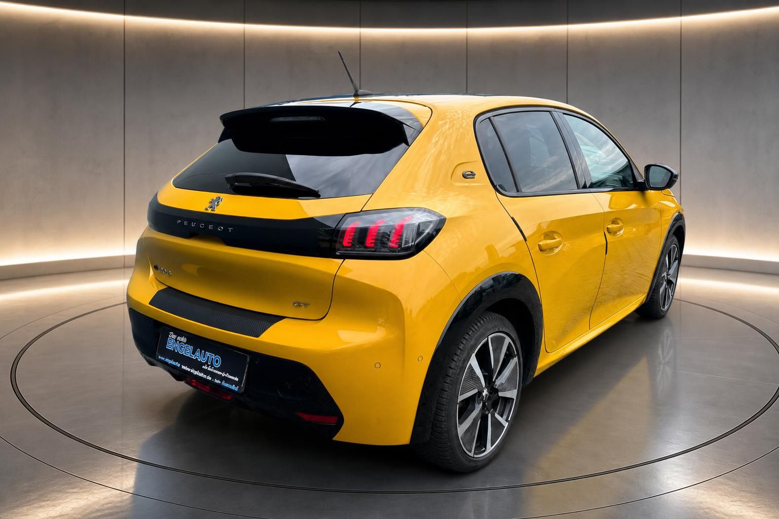 Peugeot e-208 GT gelb, Heck-Seitenansicht auf Drehbühne