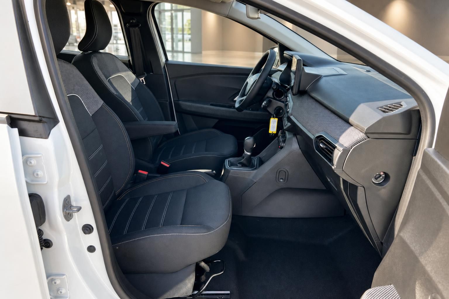 Dacia Fahrzeuginnenraum mit schwarzen Sitzen, Mittelkonsole und Schaltknauf in weißem Auto
