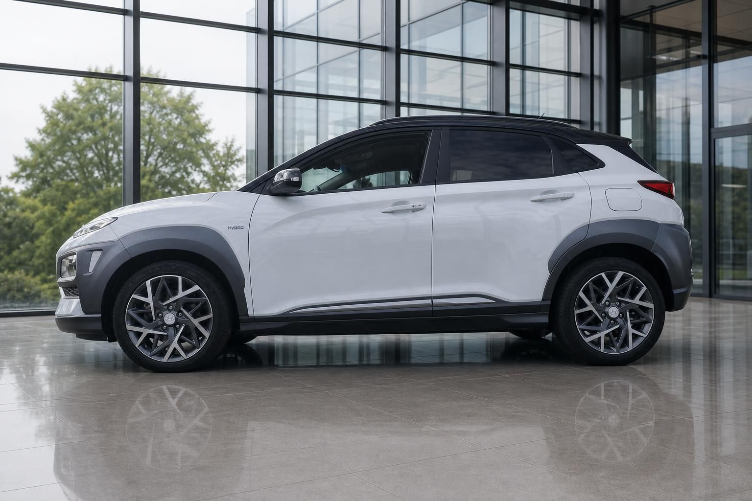 Hyundai Kona Hybrid weiss Seitenansicht links im Showroom mit zweifarb Lackierung und Sportfelgen