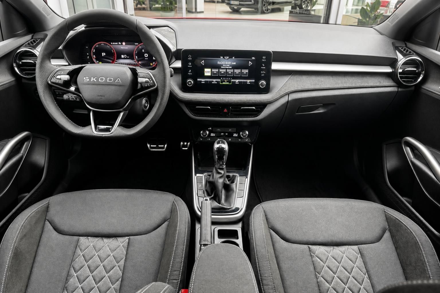 Skoda Innenraum mit schwarzem Lenkrad, Touchscreen-Display und gesteppten Sitzen in grauer Ausstattung