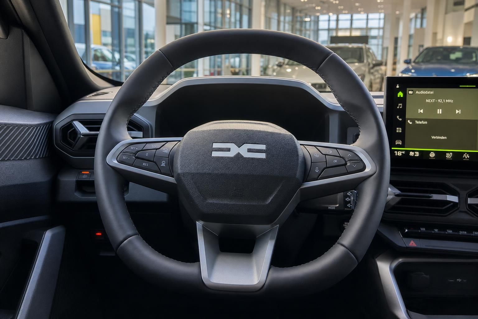 Dacia Innenraum mit Lenkrad, Multifunktionstasten und Infotainment-Display im Autohaus