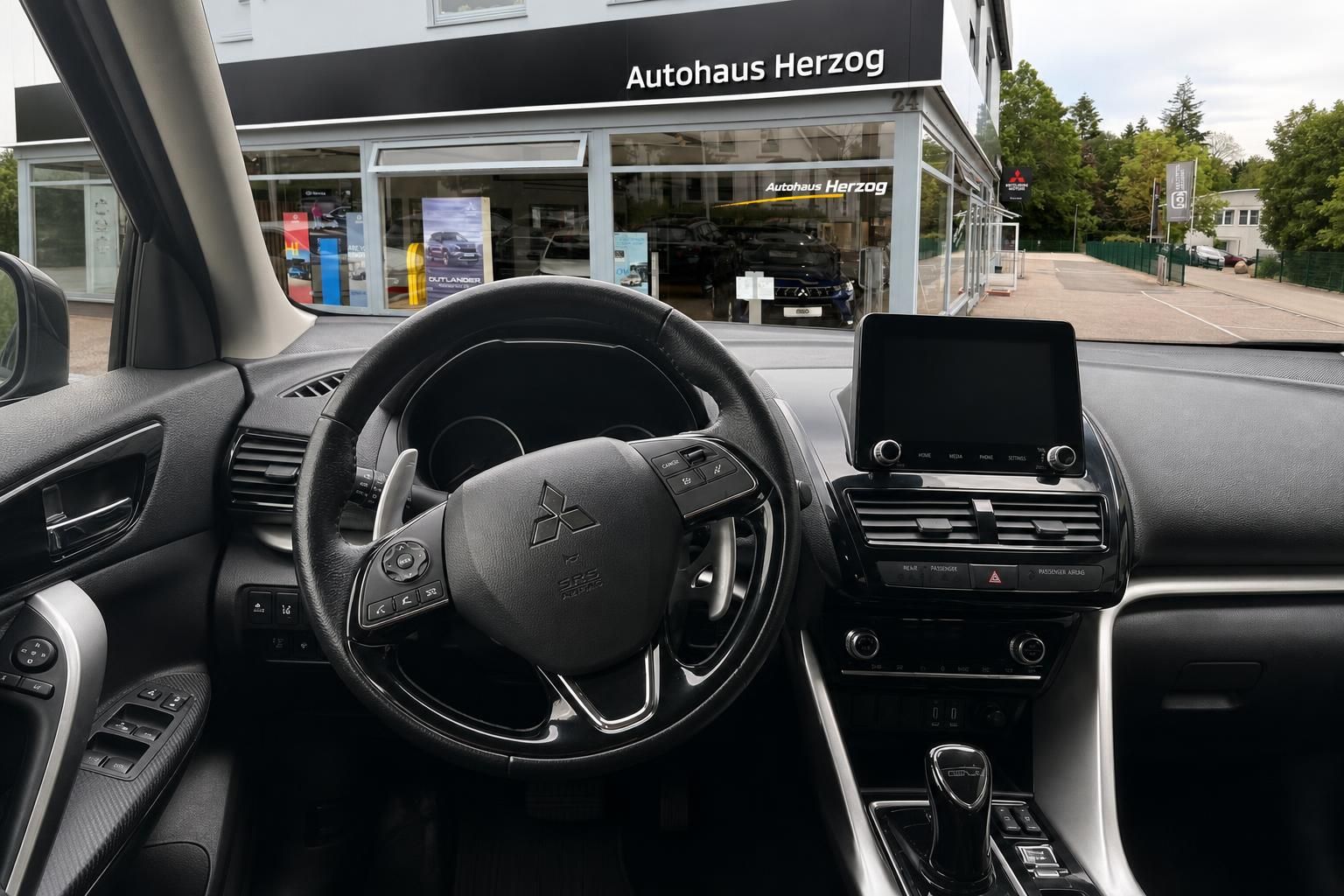 Mitsubishi Innenraum mit Lenkrad und Touchscreen vor Autohaus Herzog