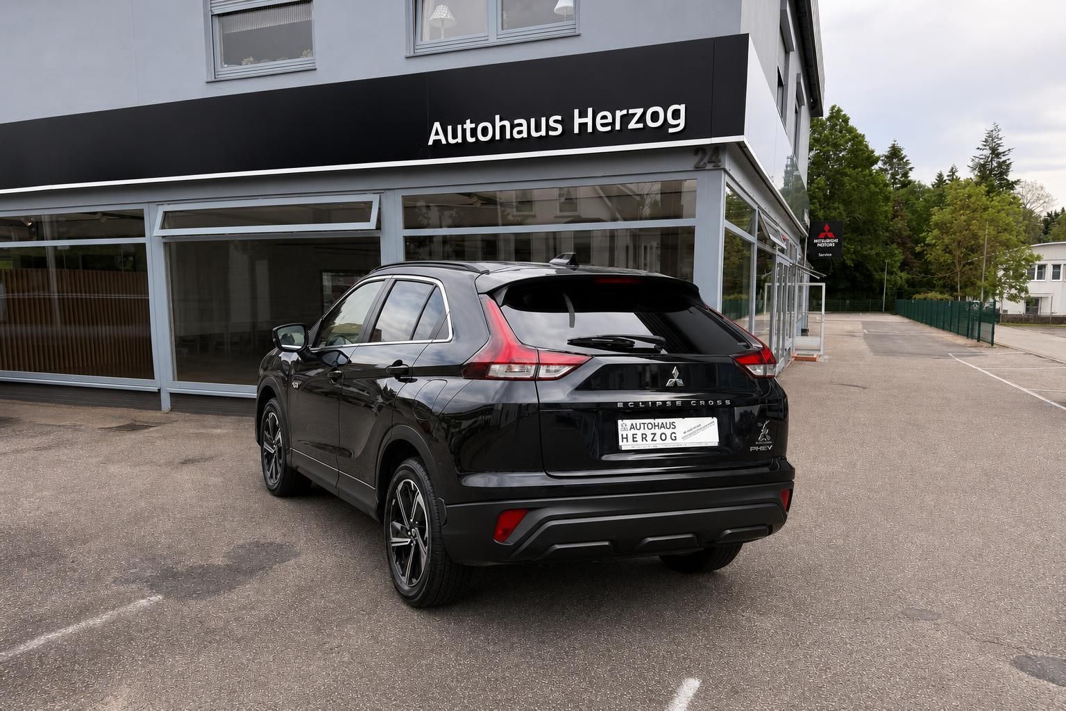 Mitsubishi Eclipse Cross PHEV schwarz, Heckansicht vor Autohaus Herzog