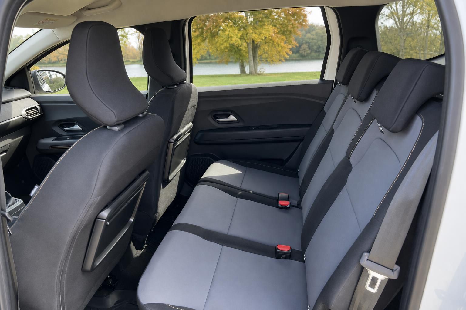 Dacia Jogger Rücksitzbank Innenraum mit grauen Sitzen und Blick durch Seitenfenster auf Park