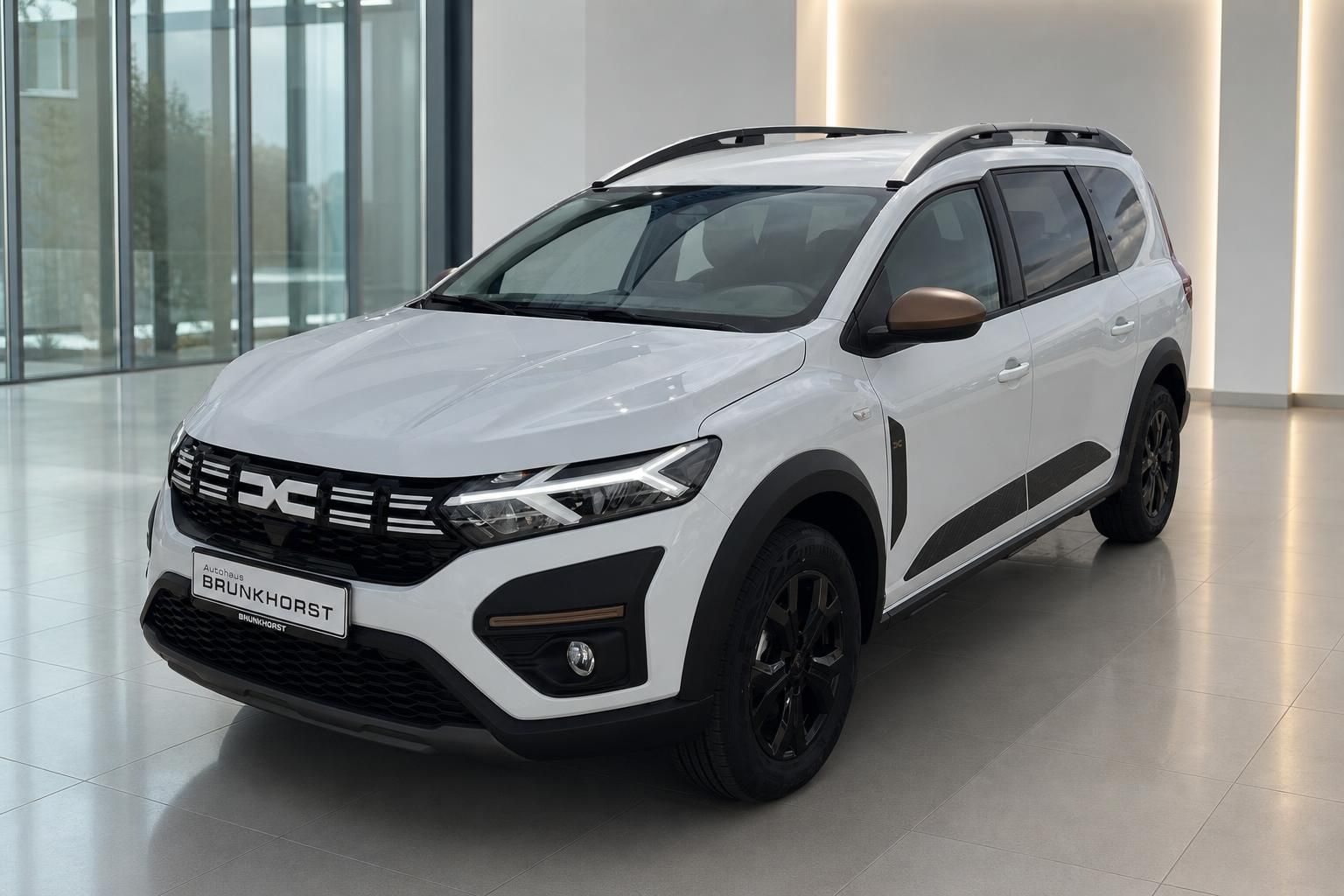 Dacia Jogger weiß Seitenansicht schräg vorne im Autohaus mit schwarzen Kunststoffverkleidungen
