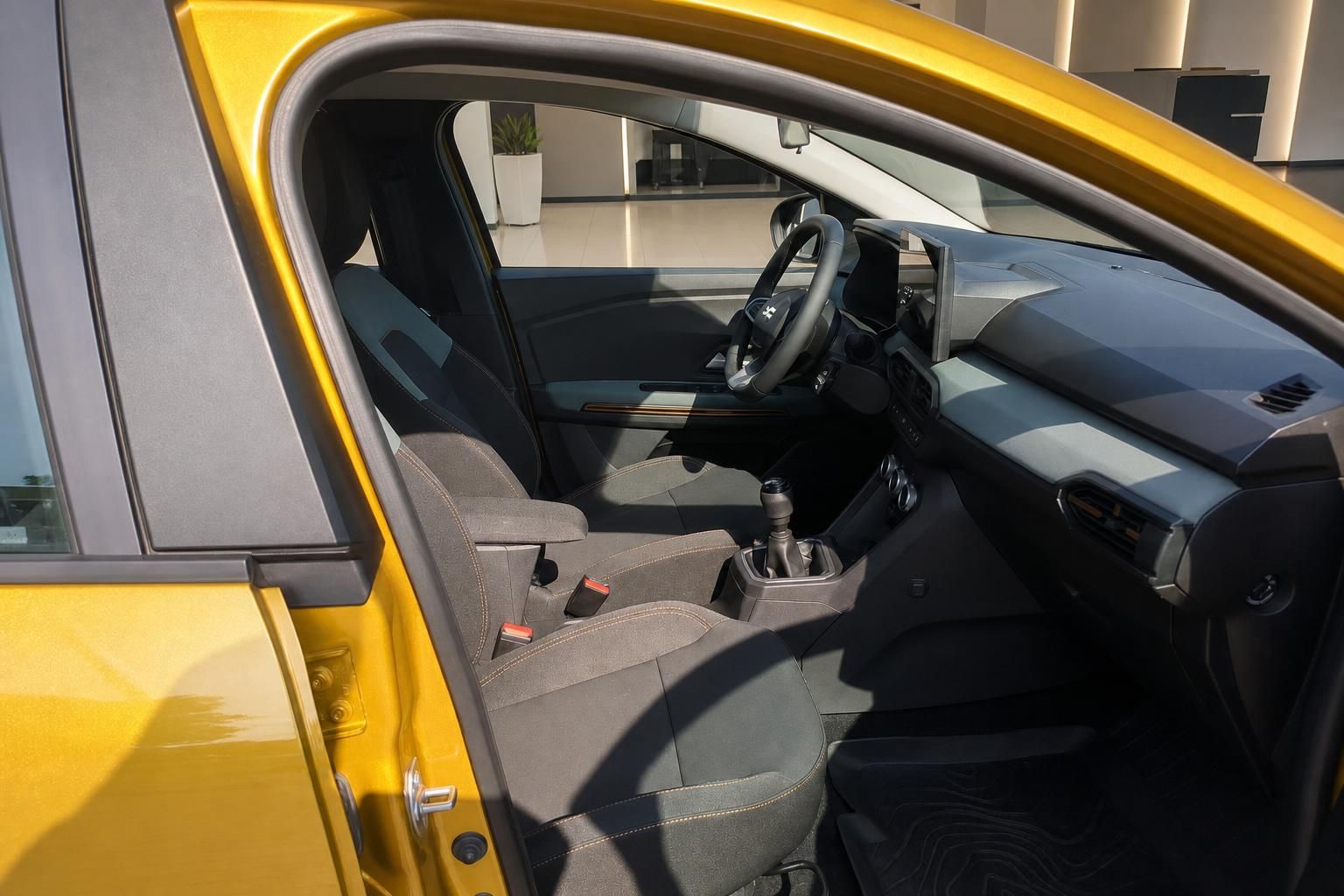 Dacia Sandero Innenraum gelb – Fahrersitz, Schaltgetriebe und Cockpit durch offene Tür