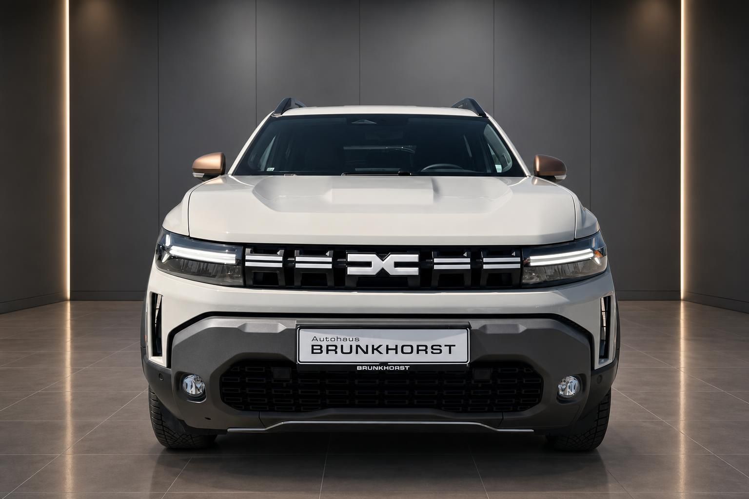 Dacia SUV Frontansicht in weiss mit markanter Kuehlergrill und LED-Scheinwerfern im Autohaus