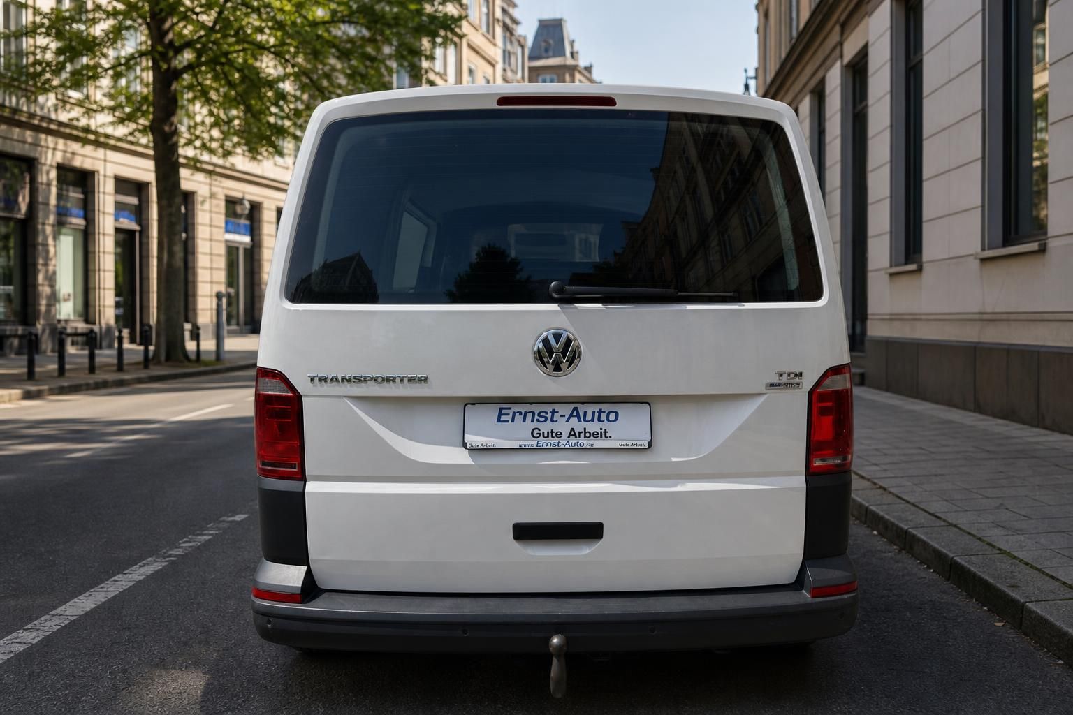 VW Transporter weiß Heckansicht mit Ernst-Auto Kennzeichen auf Stadtstraße
