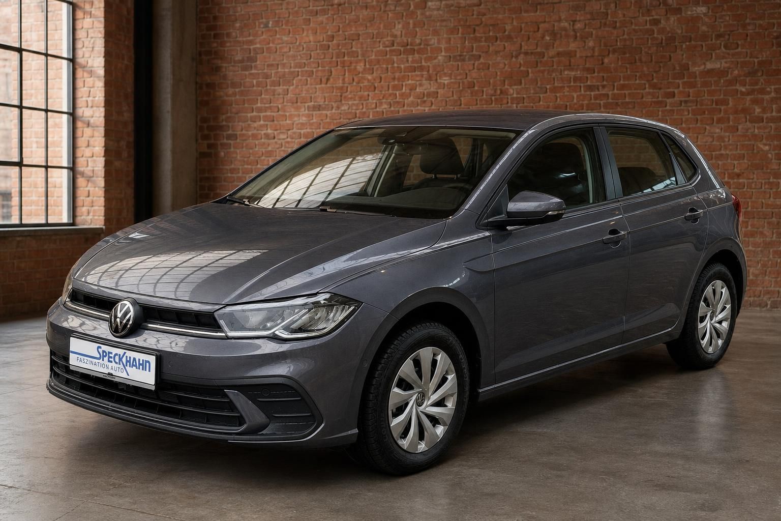VW Polo grau Frontansicht schraeg in Loft mit Backsteinwand