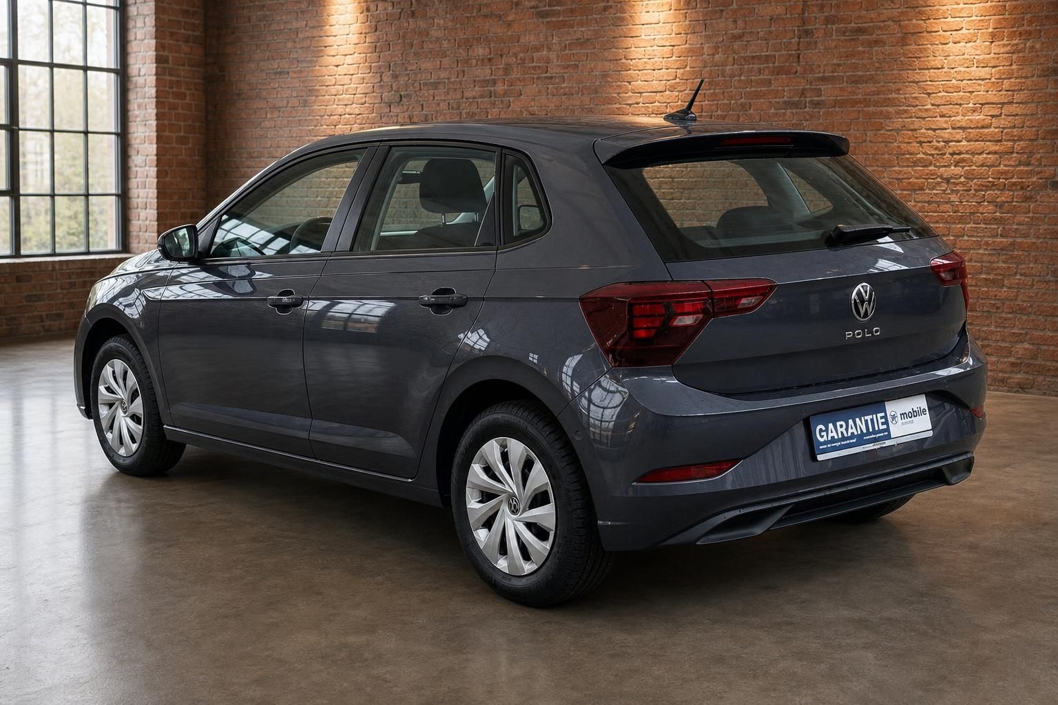 VW Polo grau Heckansicht schraeg vor Backsteinmauer
