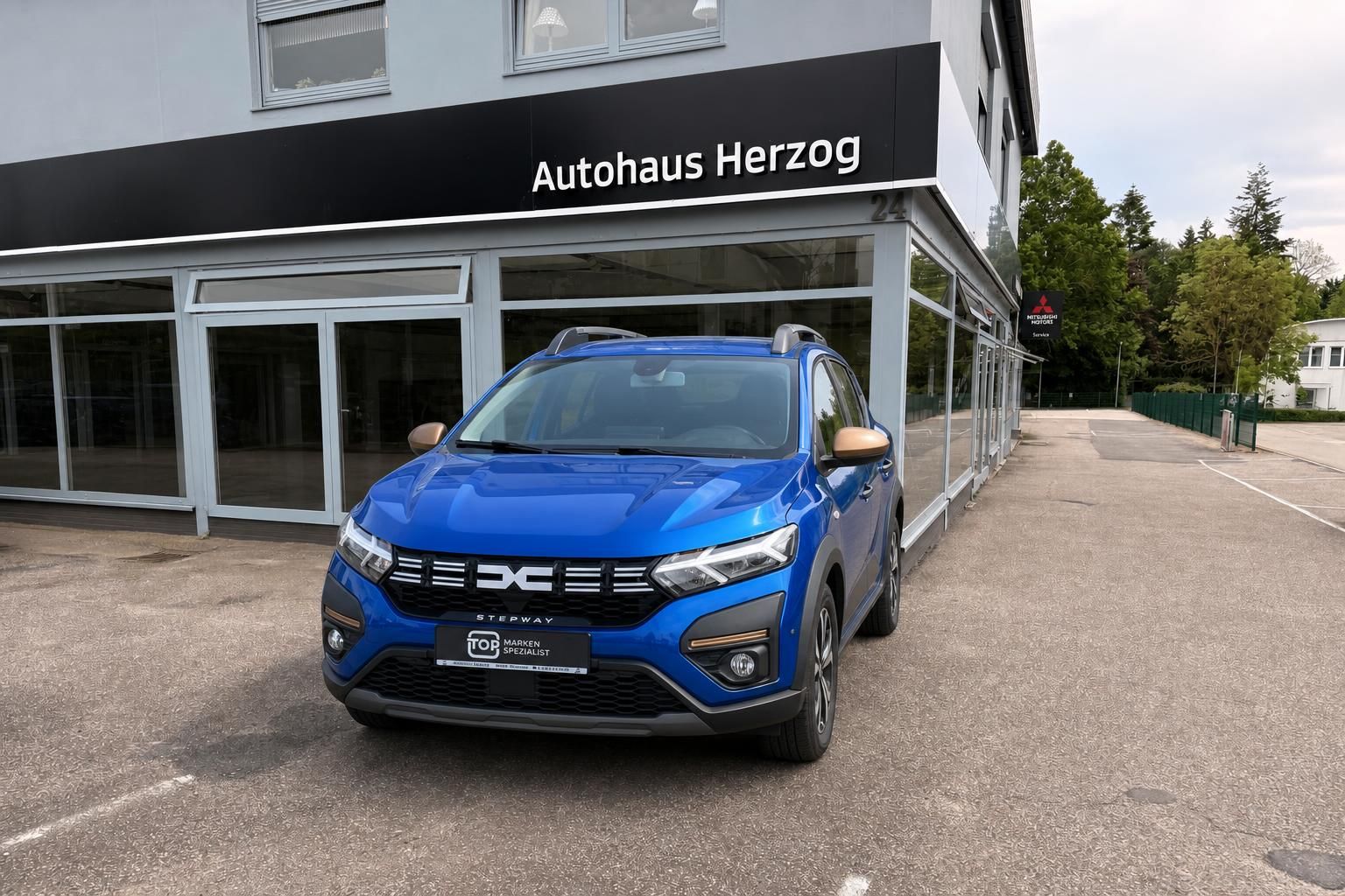 Blauer Dacia Stepway SUV Frontansicht vor Autohaus Herzog Showroom