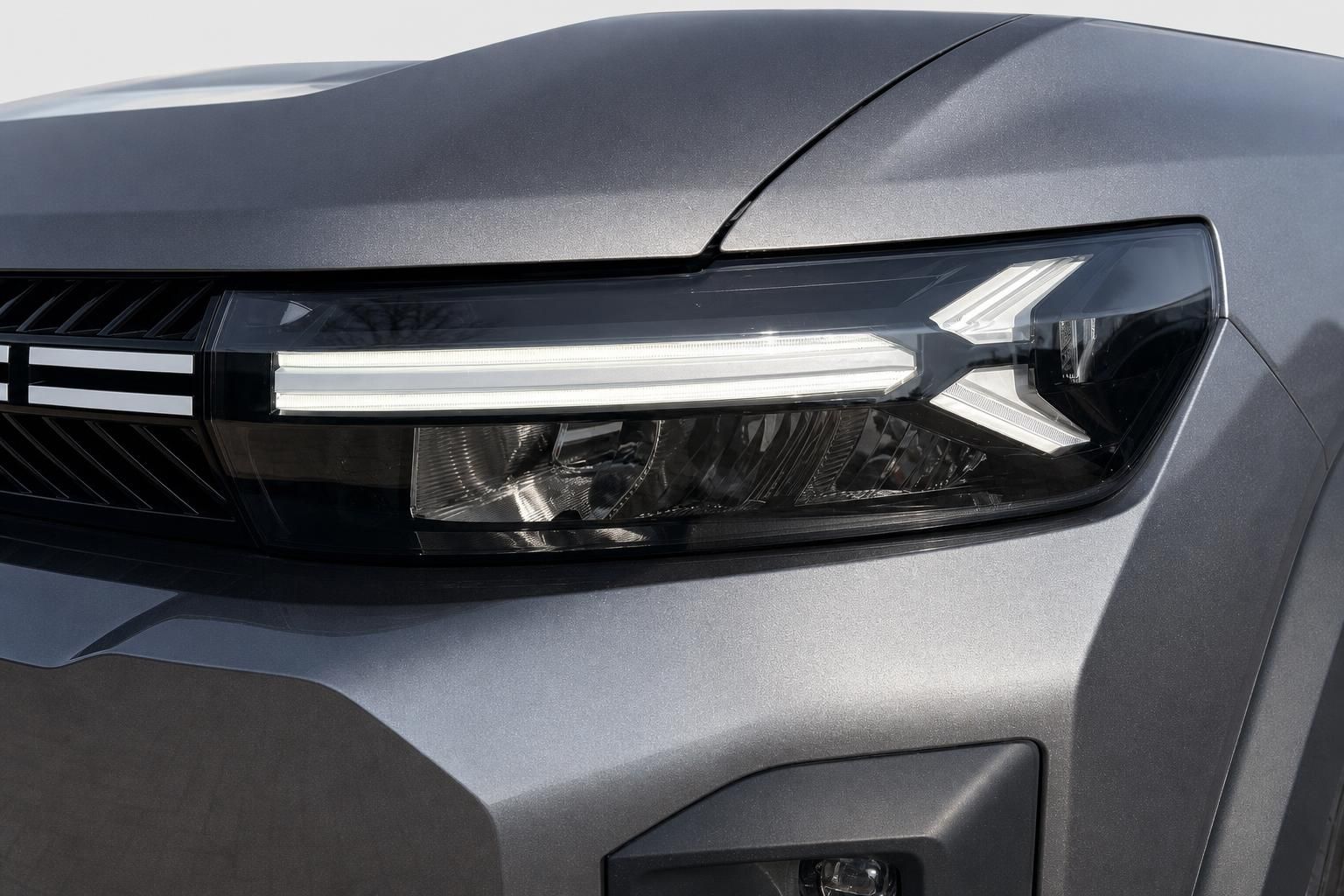 Nahaufnahme LED-Scheinwerfer eines grauen Dacia SUV
