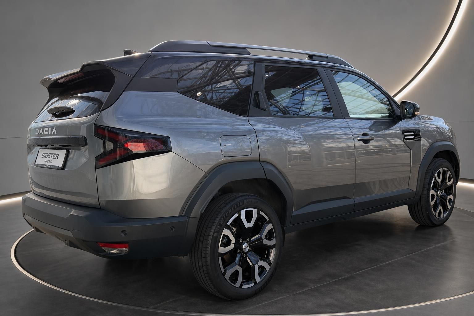 Dacia Bigster Hybrid grau Heckansicht schraeg im Showroom