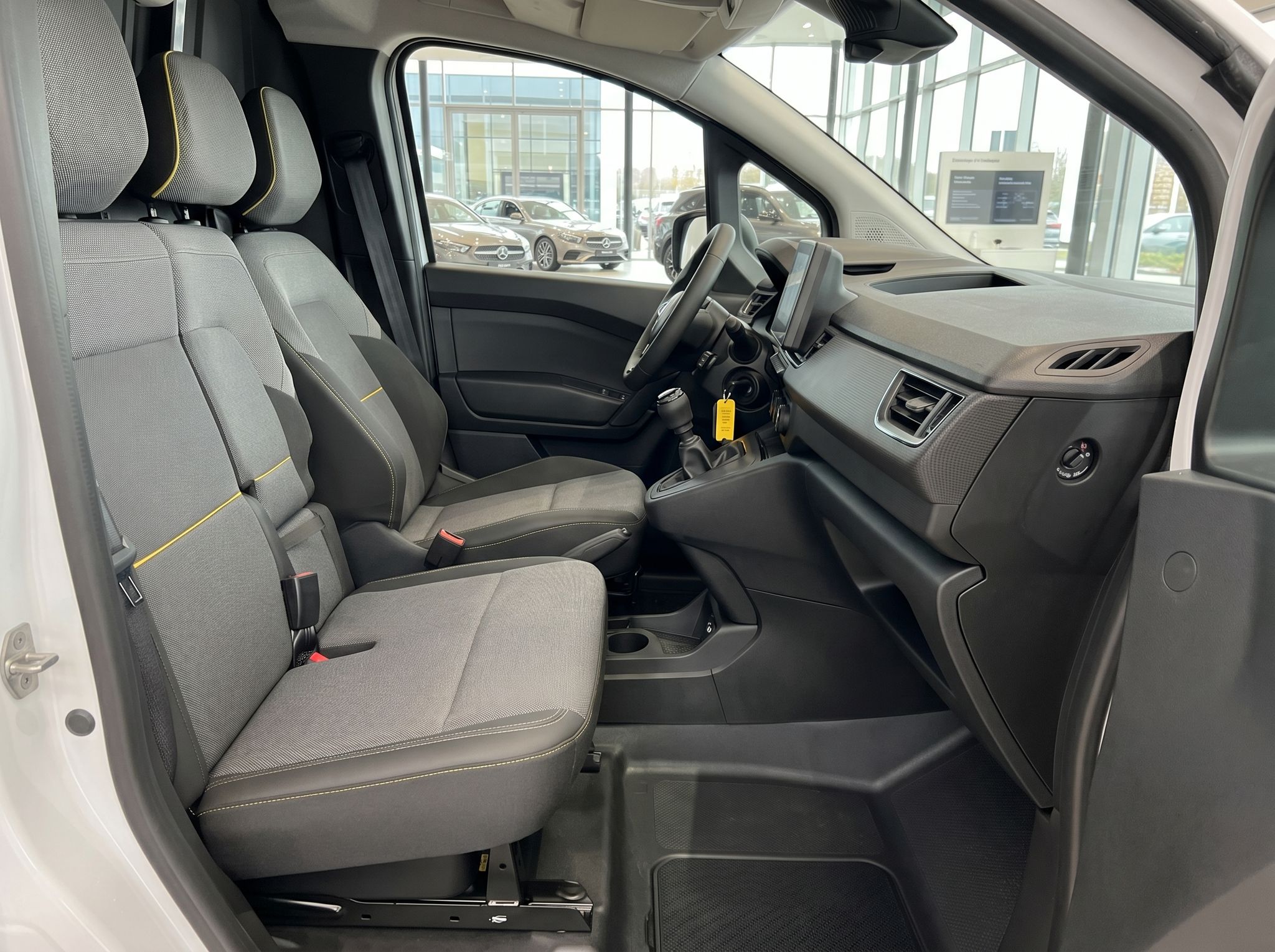Geräumiger Fahrzeuginnenraum mit grauen Stoffsitzen und gelben Akzenten